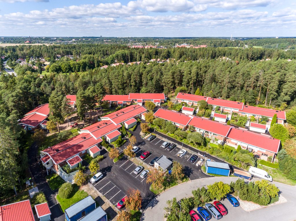 Kuva Vason omistamasta kiinteistöstä Puutakuja 3, Turku ylhäältä päin. Katot ovat punaiset, keskellä näkyy asfaltoitu parkkipaikka. Ympärillä on vihreää metsää, taivas on sininen ja puolipilvinen.