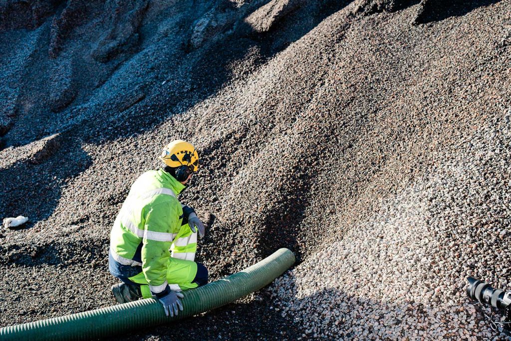 AuraCleanin työntekijä imee sepeliä paineauton letkulla, jotta sepeli voidaan puhaltaa uuteen kohteeseen suurtehopuhalluksen avulla.